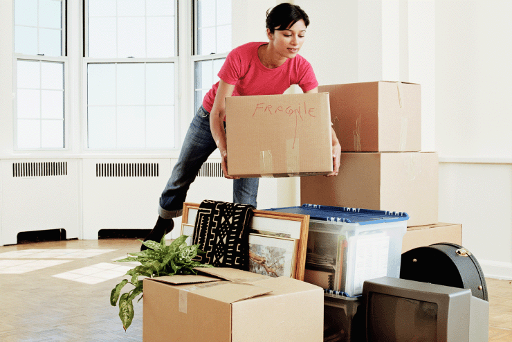 A woman in a red shirt moves into her new home.