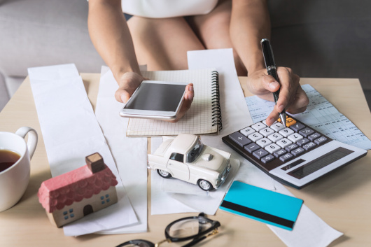 Woman using calculator and phone to manage debt.