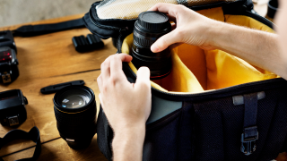 A person pulls a lens out of a camera bag.