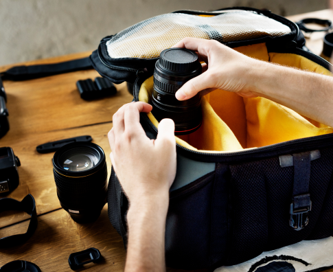 A person pulls a lens out of a camera bag.