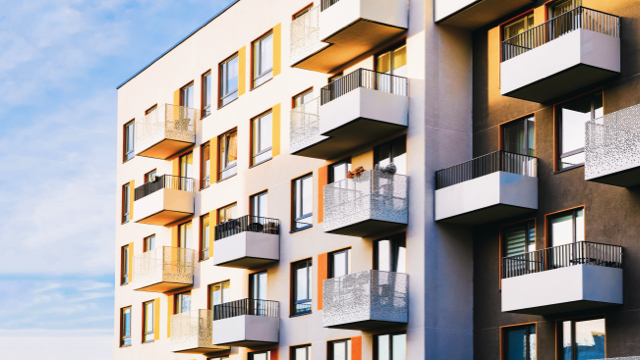 The sun shines on a high-rise condo with several patio balconies.