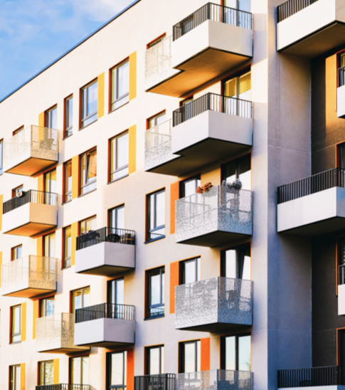 The sun shines on a high-rise condo with several patio balconies.