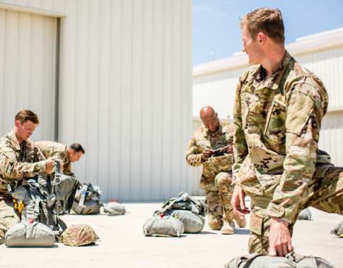 Military members in uniform sort equipment for a mission.