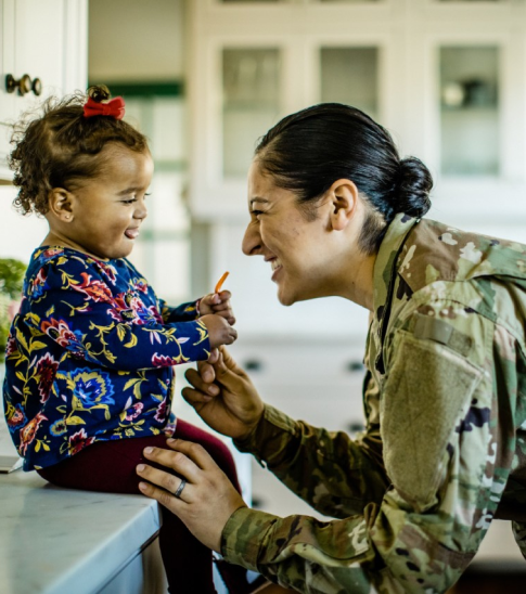 Soldier smiling at child sitting down.