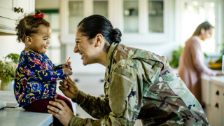 Soldier smiling at child sitting down.