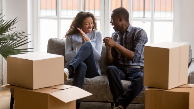 Two people on a couch laugh after moving into their new home.