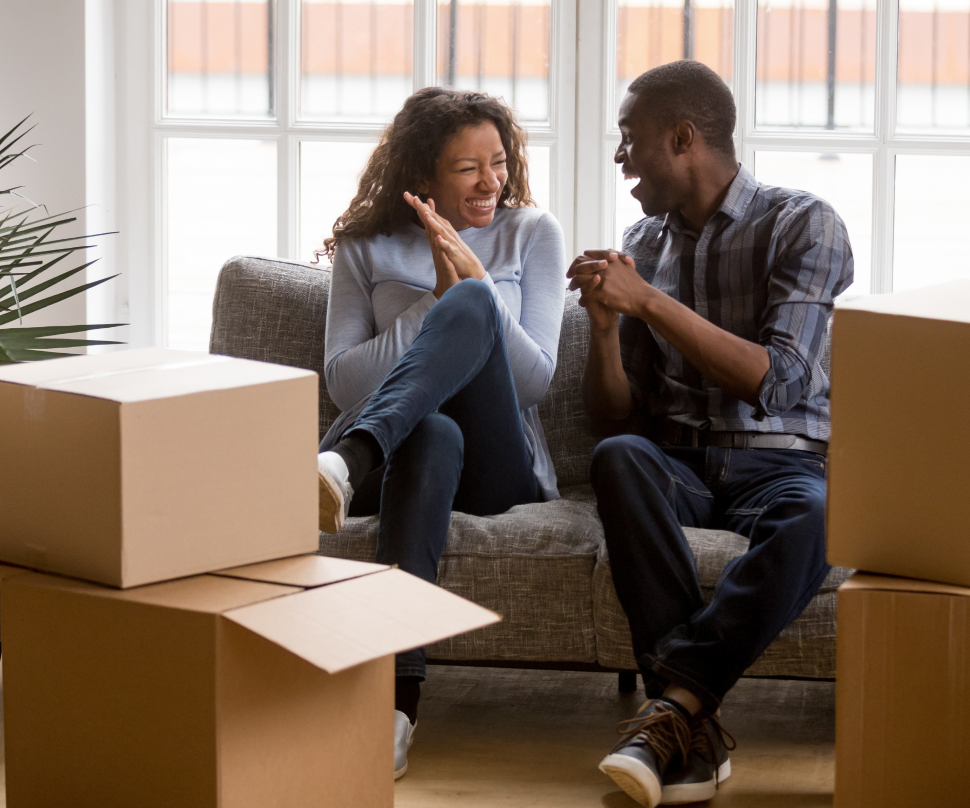 Two people on a couch laugh after moving into their new home.