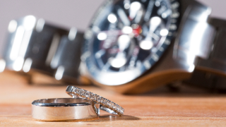 Two rings on a table with a watch in the background