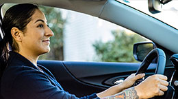 A smiling person drives their car.